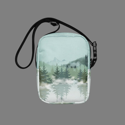 Image: Winter Forest Small Cross Body Bag. This nature inspired sling bag has an ombre snowy mountain print that fades from a blue gray sky to mountains and pine trees to white snow. This mini backpack has a zipper closure and two storage pockets for hands free outdoor adventures. Great for tween girls, teens and ladies, by jaecrece