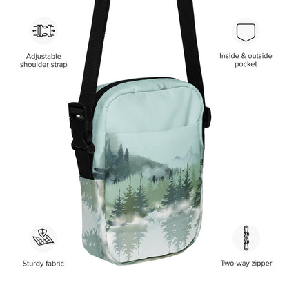 Image: Winter Forest Small Cross Body Bag. This nature inspired sling bag has an ombre snowy mountain print that fades from a blue gray sky to mountains and pine trees to white snow. This mini backpack has a zipper closure and two storage pockets for hands free outdoor adventures. Great for tween girls, teens and ladies, by jaecrece