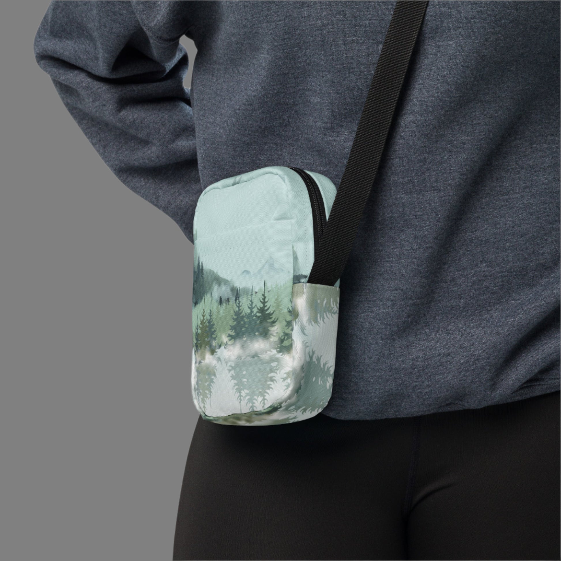 Image: Winter Forest Small Cross Body Bag. This nature inspired sling bag has an ombre snowy mountain print that fades from a blue gray sky to mountains and pine trees to white snow. This mini backpack has a zipper closure and two storage pockets for hands free outdoor adventures. Great for tween girls, teens and ladies, by jaecrece