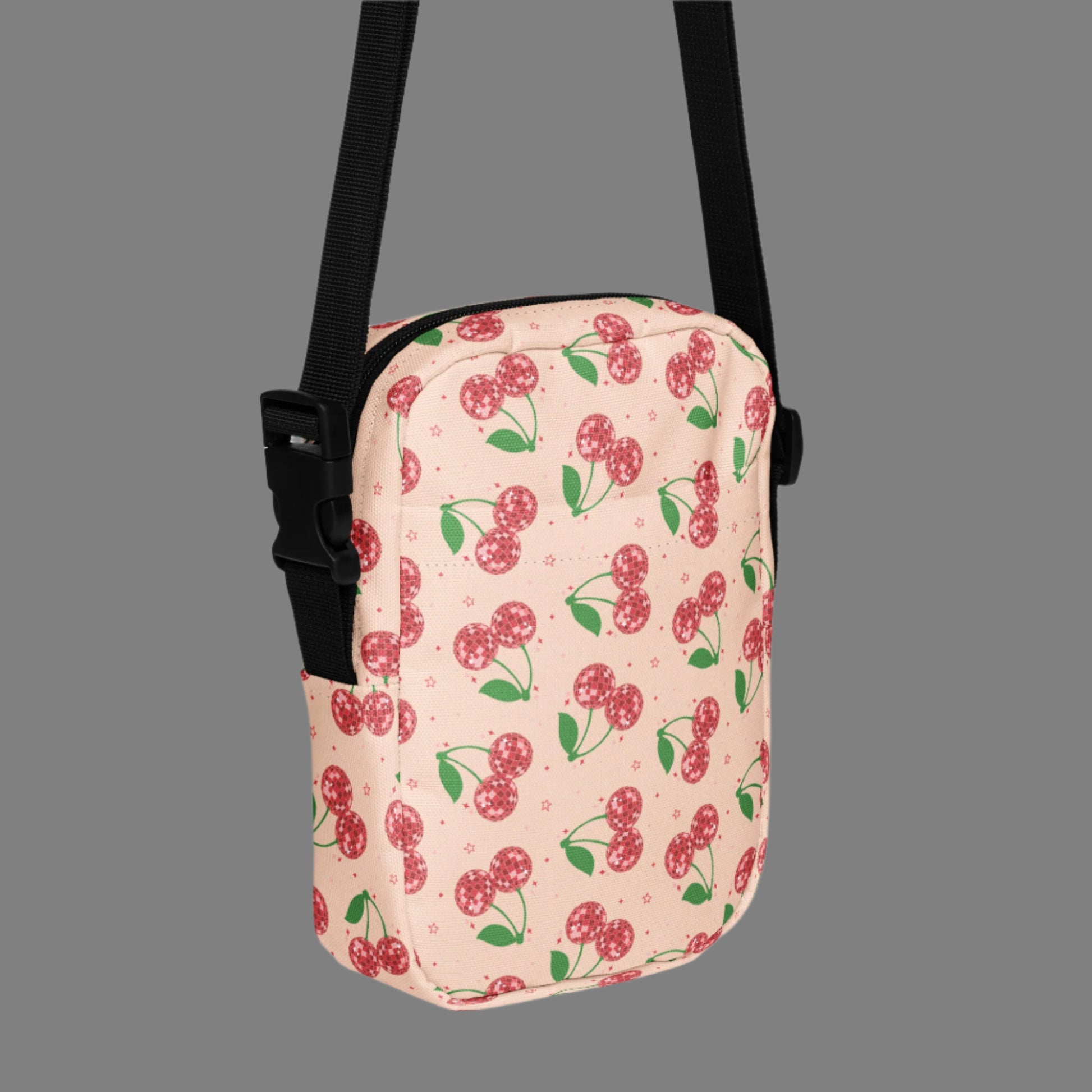 Image: Pink Utility Crossbody bag with a pattern of red disco ball cherries and stars. A great small tote to be worn across the chest, hips, waist. Perfect  as a Valentines Day gift or for outdoor activities, such as parades, hiking or the amusement park, by jaecrece