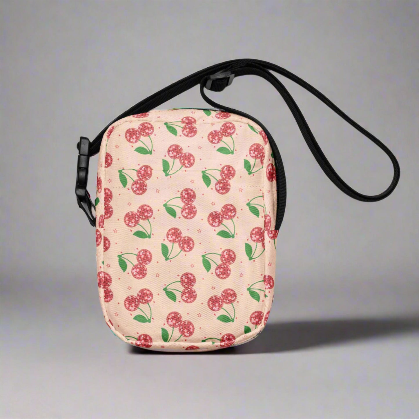 Image: Pink Utility Crossbody bag with a pattern of red disco ball cherries and stars. A great small tote to be worn across the chest, hips, waist. Perfect  as a Valentines Day gift or for outdoor activities, such as parades, hiking or the amusement park, by jaecrece