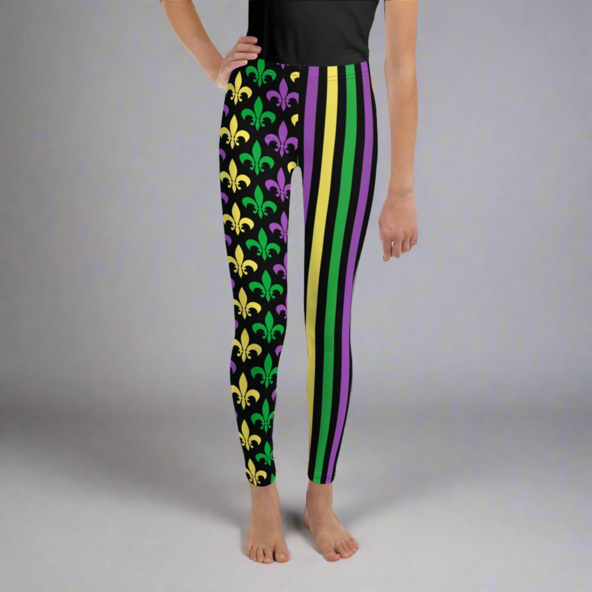 Alt text: "Mardi Gras Stripes and Fleur de Lis Youth Leggings, size 8-20. Black leggings with a fleur de lis pattern on one leg and bright green, purple, and yellow stripes on the other. Elastic, soft, and durable with vibrant colors. Part of a matching collection for younger children and women, each pair is precision-cut and hand-sewn for a perfect fit."