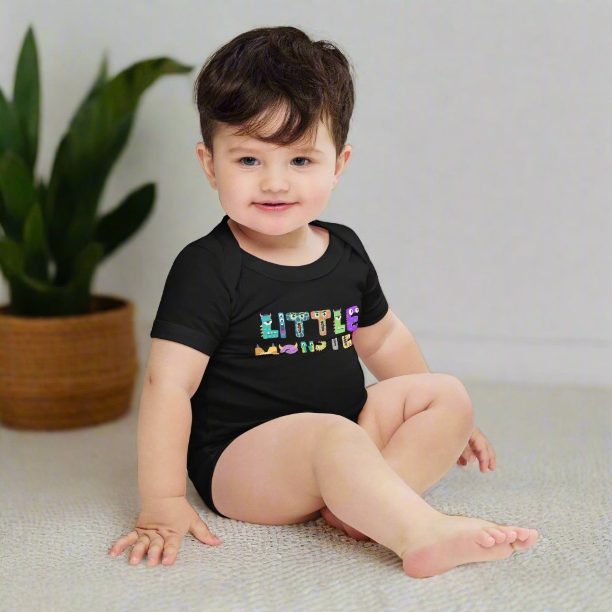 Baby onesie available in black or white. Features the words Little Monster, and each letter is in the shape of a cute cartoon monster, by jaecrece