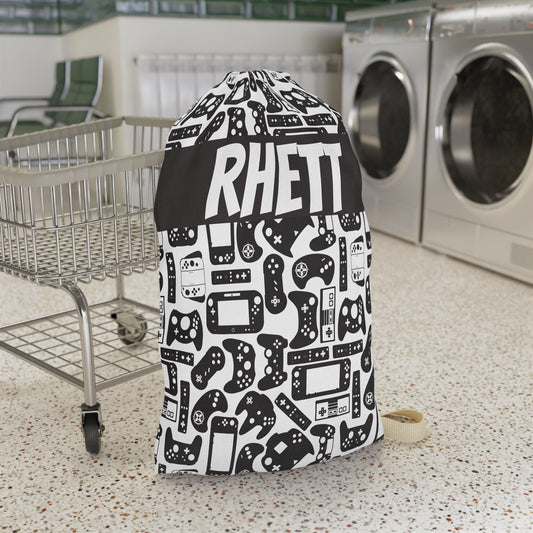 Laundry bag with a black and white pattern and 'RHETT' personalization in a laundromat.
