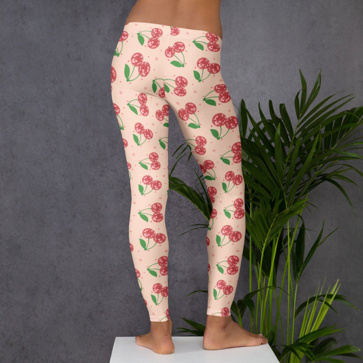 Image: Playful cherry aesthetic women’s leggings featuring disco ball cherries on a bright pink background, full length mid rise leggings ideal for everyday wear, casual outfits, athleisure looks, travel days, lounge wear, retro inspired fashion, and bold statement style