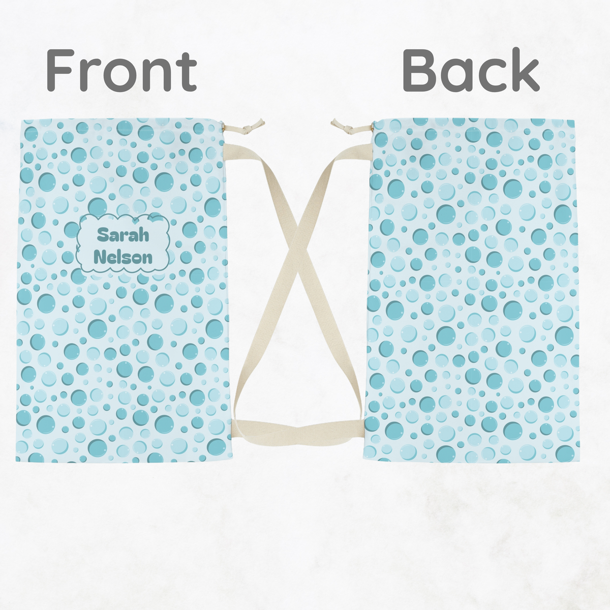 Front and back views of an aqua bubble print drawstring laundry bag, displayed side by side to show the colorful pattern, fabric construction, and plain cream drawstrings. This reusable laundry bag is a fun, practical choice for kids, tweens, and teens packing for summer camp, sleepovers, dorm life, and travel.