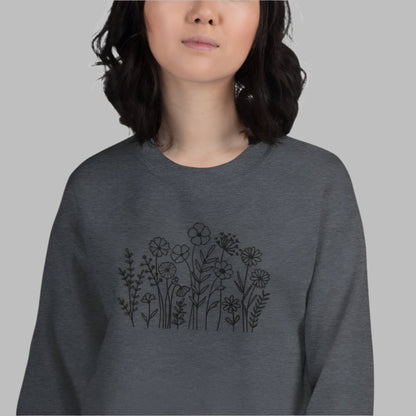 Image: A cozy dark grey sweatshirt with delicate black wildflower embroidery across the chest, showcasing a minimalist yet elegant botanical design. The soft fabric drapes effortlessly, offering comfort for everyday wear. This floral nature crewneck is perfect for layering, adding a subtle floral charm to casual outfits. A thoughtful gift for plant lovers or those who appreciate nature-inspired fashion, by jaecrece.