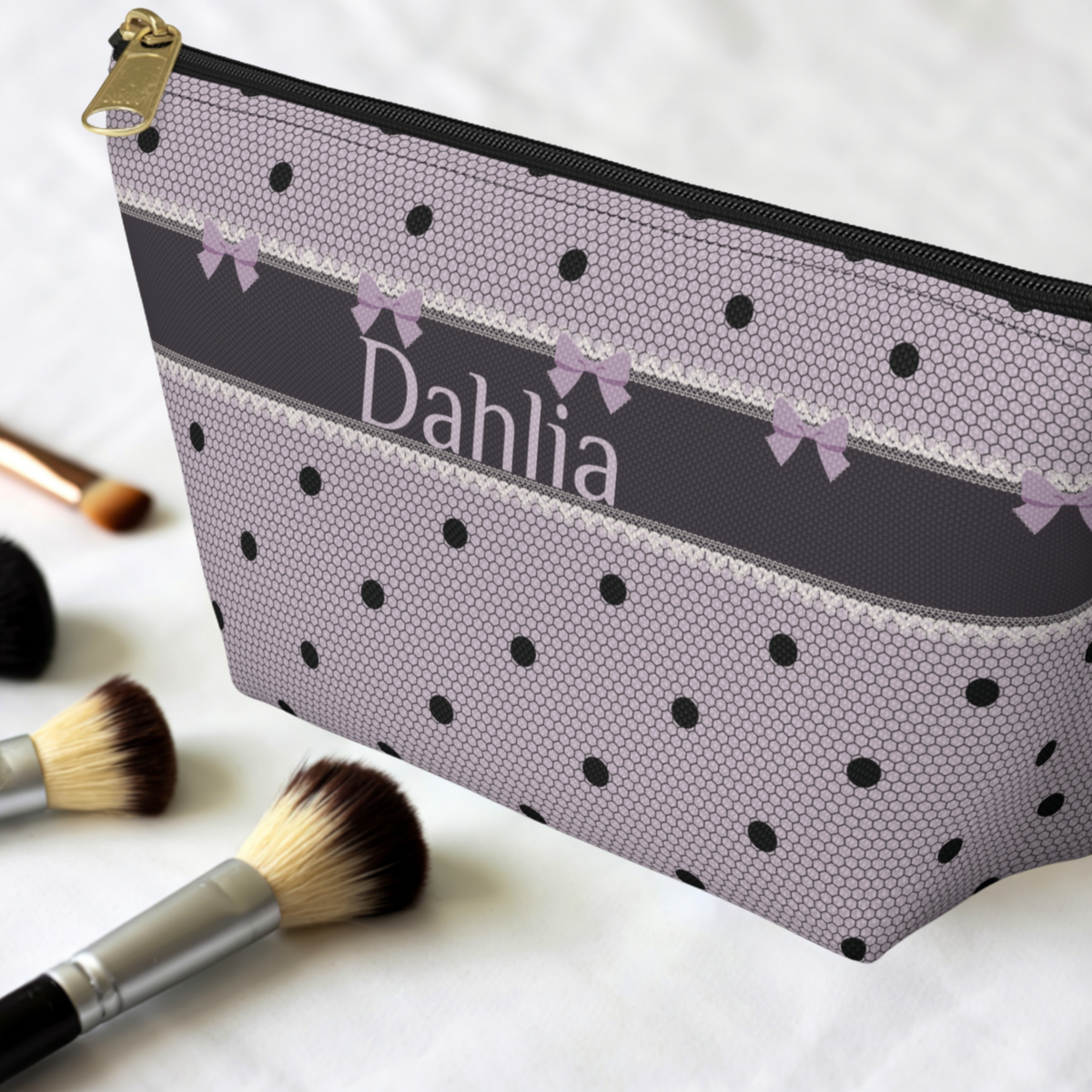 Custom monogram travel makeup pouch featuring a lavender and black gothic coquette design with bows, polka dots and lace inspired detailing. This personalized makeup bag is made for organizing cosmetics, skincare and toiletries while traveling. Customize the canvas zipper pouch with a name or initials for a distinctive dark romance accessory