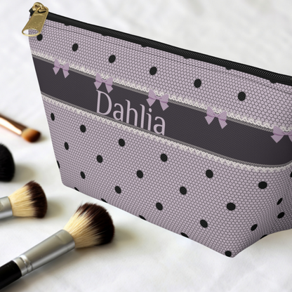 Custom monogram travel makeup pouch featuring a lavender and black gothic coquette design with bows, polka dots and lace inspired detailing. This personalized makeup bag is made for organizing cosmetics, skincare and toiletries while traveling. Customize the canvas zipper pouch with a name or initials for a distinctive dark romance accessory