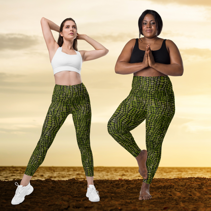 Two women wearing green snake print patterned leggings and sports bras against a sunset background.