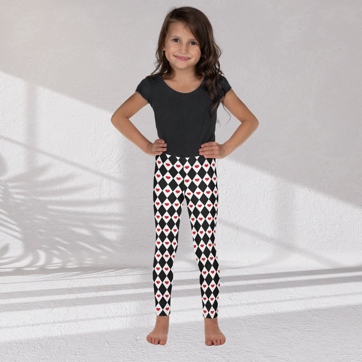 The Harlequin Hearts leggings feature a classic black and white diamond pattern with red hearts scattered across the fabric. Their playful design can be styled for Valentine's Day, a themed school event, or an imaginative Queen of Hearts costume. The soft microfiber fabric has four way stretch and an elastic waistband for comfortable movement and an easy fit throughout the day.