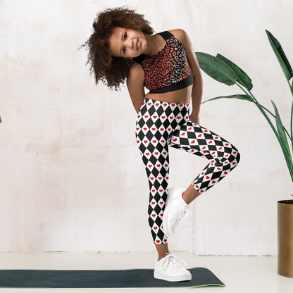 Black and white girls leggings feature a repeating harlequin diamond pattern decorated with bright red hearts. The playful design has a whimsical look that works for everyday outfits, Valentine's Day clothing, or a Queen of Hearts inspired costume. The full length leggings have a high waisted fit and soft stretchy fabric designed for comfortable movement during school, play, or lounging.