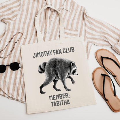 Natural cotton canvas Jimothy Fan Club tote showing personalized member name, playful raccoon artwork, and vintage inspired lettering. Personalized Jimothy tote bag designed as a funny gift for raccoon lovers, meme lovers, animal lovers, Seattle fans, and Jimothy fans.