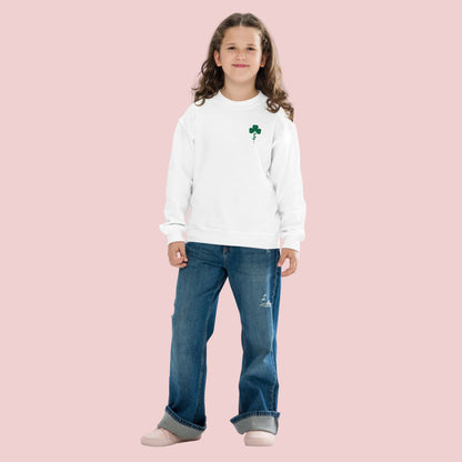 Child wearing white youth sweatshirt with green embroidered lucky shamrock clover design. St Patricks Day kids sweatshirt made with Gildan 18000B crewneck, festive lucky clover embroidery perfect for school celebrations, parades, and family matching outfits.