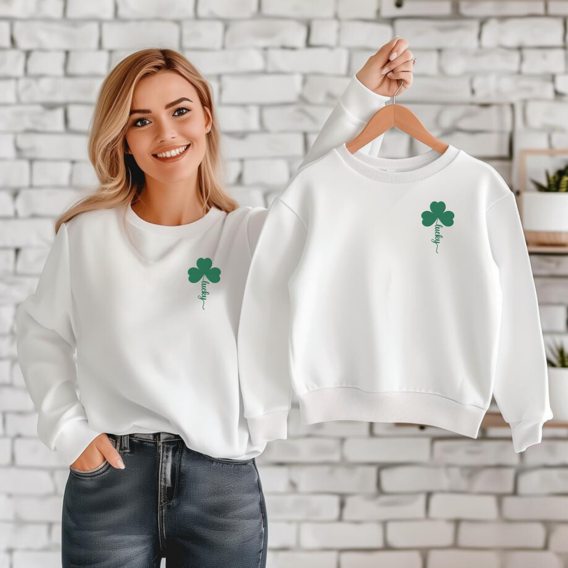 Image: Mom wearing matching white St Patricks Day lucky shamrock embroidered sweatshirt while holding the youth size version. Mommy and me matching St Patrick's Day outfits featuring green four leaf clover Lucky embroidery. This white crewneck pullover has embroidered green four leaf clover, and stem of the  clover spells Lucky. This St. Pattys Day pullover sweater is also available in childrens sizes, for family matching opportunities, by jaecrece