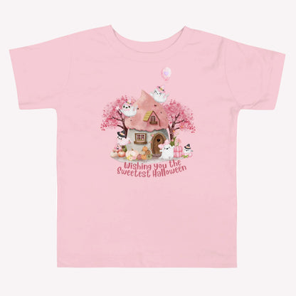 Pink Halloween toddler shirt with smiling and playful ghosts, pastel pumpkins, flowers, autumn trees, and a charming haunted cottage. The phrase Wishing You the Sweetest Halloween is featured in large pink lettering for a cheerful and whimsical Halloween look.