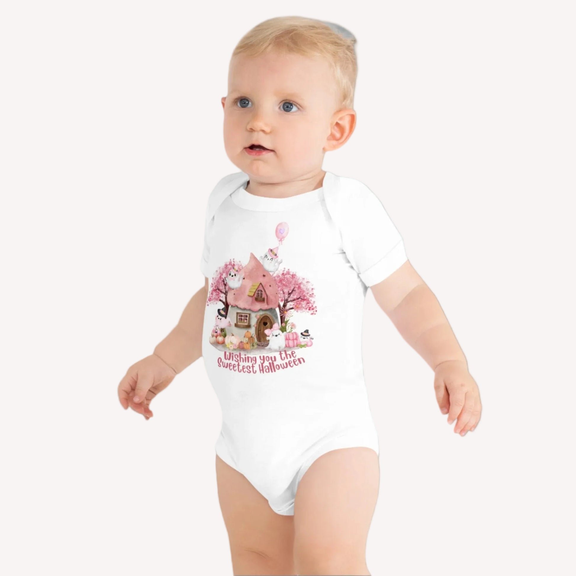 Image: A charming Halloween baby outfit for little girls, this pink onesie showcases a fairy tale cottage surrounded by smiling pumpkins and ghosts. Ideal for newborn photo shoots, October baby showers, and toddler Halloween fashion, this soft and stylish one piece is a customer favorite, by jaecrece.