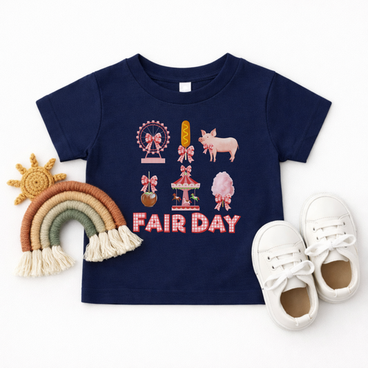 Flatlay of a Navy Fair Day shirtt, featuring a cute vintage inspired fair design with a Ferris wheel, cotton candy, carousel, corn dog, pink pig, caramel apple and gingham bows.
