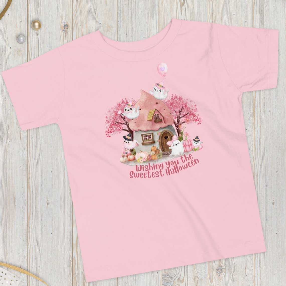 Pink toddler tshirt with a storybook cottage, pink trees, pink pumpkins and five sweet ghosts. The text reads Wishing you the sweetest halloween, by jaecrece