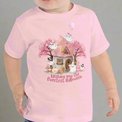 Pink toddler tshirt with a storybook cottage, pink trees, pink pumpkins and five sweet ghosts. The text reads Wishing you the sweetest halloween, by jaecrece