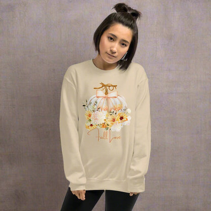 Fall Love Ladies Sweatshirt, this is a Sand colored Gildan Sweatshirt, with a graphic of a white pumpkin with a peach ribbon. The pumpkin is surrounded by a garland of fall leaves and flowers, with the text- Fall Love, by jaecrece