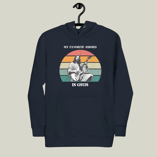 Hanging mockup of the “My Favorite Chord Is GSUS” unisex hoodie, displayed on a wooden hanger to highlight its soft fleece fabric and relaxed fit. Featuring a witty Christian pun that blends music and faith, this cozy hoodie is perfect for musicians, worship leaders, and church band members. Made from a cotton-poly blend and available in sizes S–3XL, it’s ideal for gifts or everyday wear.

