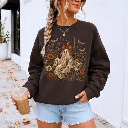 Gothic cottagecore inspired Halloween sweatshirt featuring a vintage ghost sitting on a swing while blowing bubble gum. Floral and botanical details surround the ghost along with bats, lace, stars and a crescent moon for a romantic and whimsical spooky season look.