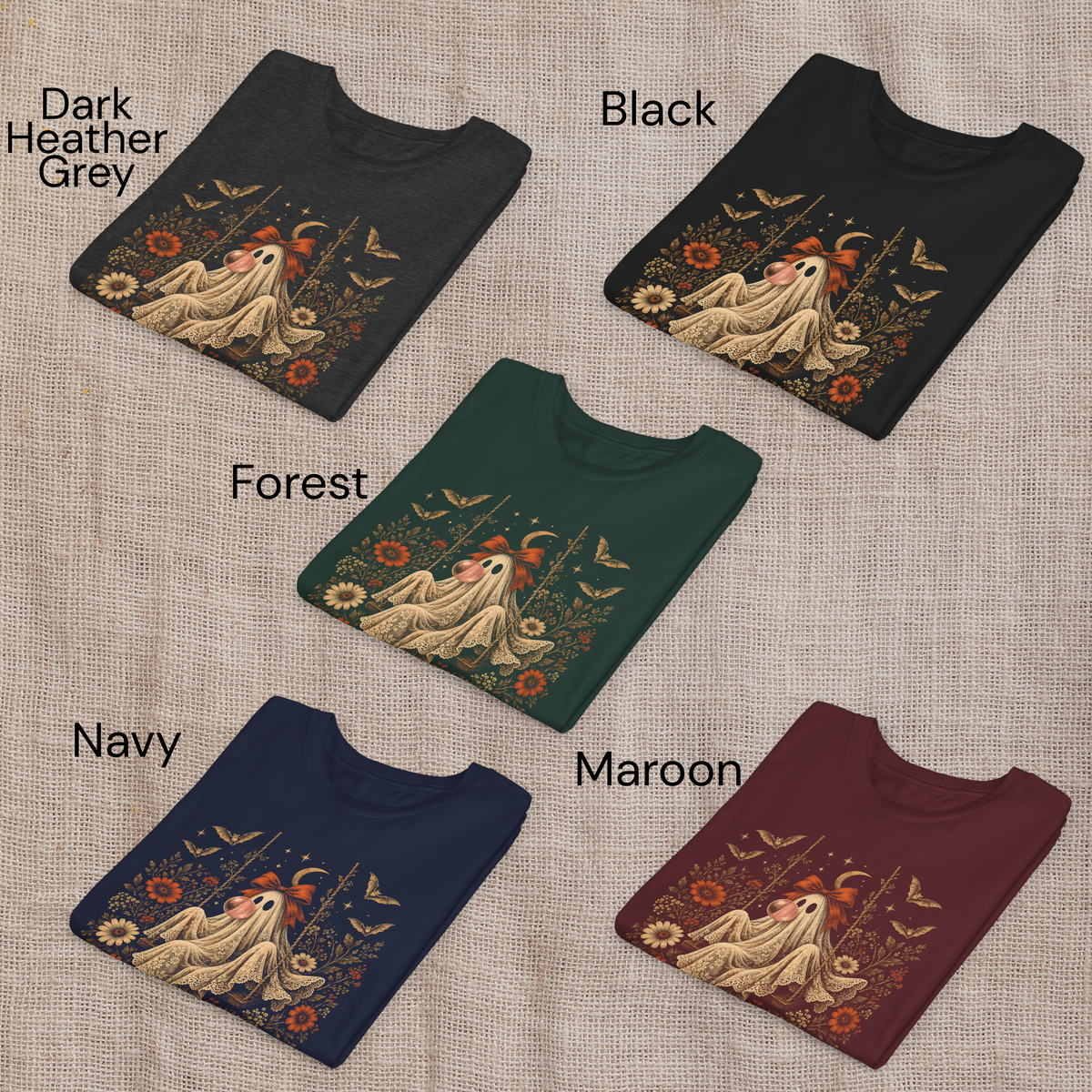 Girls Halloween T shirts shown folded in Black, Navy, Maroon, Forest Green and Dark Heather Grey. Each shirt features the whimsical vintage ghost blowing bubble gum design with orange flowers, botanical foliage, bats, stars, lace and a bow, offering classic color choices for spooky season and fall outfits.