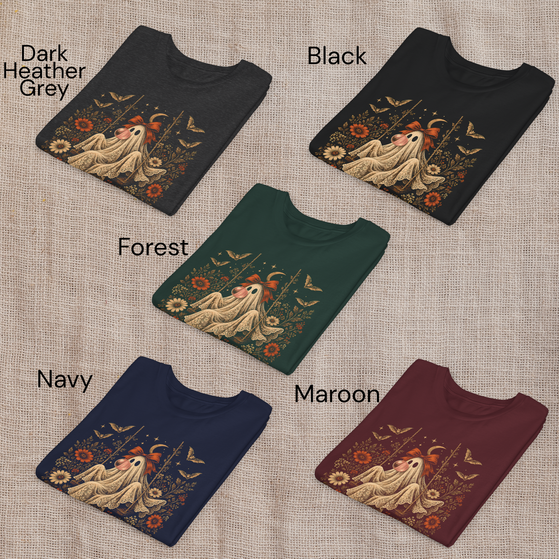 Girls Halloween T shirts shown folded in Black, Navy, Maroon, Forest Green and Dark Heather Grey. Each shirt features the whimsical vintage ghost blowing bubble gum design with orange flowers, botanical foliage, bats, stars, lace and a bow, offering classic color choices for spooky season and fall outfits.