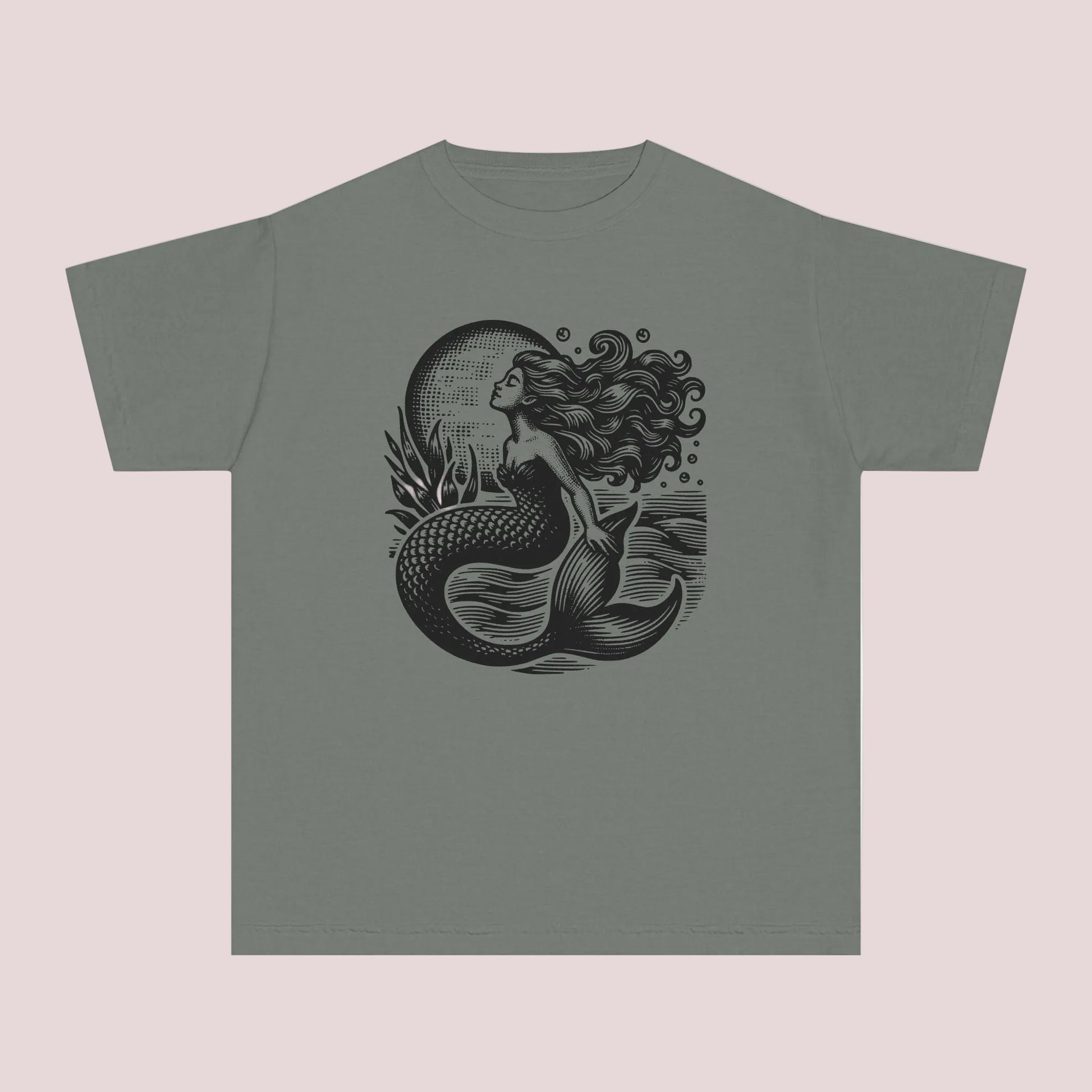 Vintage coastal girls t shirt featuring a detailed linocut inspired mermaid graphic with dark ocean waves and moonlit seaside artwork. Printed on a soft garment dyed Comfort Colors youth tee designed for comfort style and everyday wear. Perfect for beach lovers mermaid fans seaside vacations summer camps coastal family photos and trendy ocean aesthetic outfits. Relaxed fit cotton graphic shirt pairs perfectly with denim shorts leggings and layered beachy fashion looks.