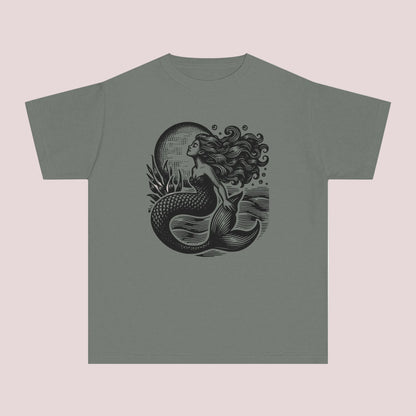 Vintage coastal girls t shirt featuring a detailed linocut inspired mermaid graphic with dark ocean waves and moonlit seaside artwork. Printed on a soft garment dyed Comfort Colors youth tee designed for comfort style and everyday wear. Perfect for beach lovers mermaid fans seaside vacations summer camps coastal family photos and trendy ocean aesthetic outfits. Relaxed fit cotton graphic shirt pairs perfectly with denim shorts leggings and layered beachy fashion looks.