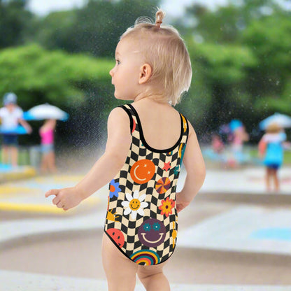Comfortable and secure toddler swimsuit with a fun checkerboard design and colorful smiley faces, stars, and daisies. Offers UPF 38–40, four-way stretch, and double-layered front for active play. Ideal for splash pads, pool days, or sunny vacations. Toddler sizes 2T–7. Part of a coordinating family swim collection with styles for girls, women, and men for the perfect group look.

