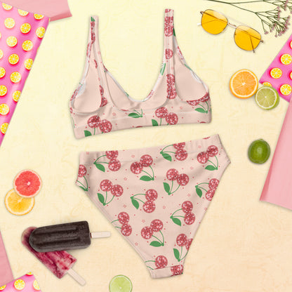 This charming two piece swimsuit features a whimsical disco cherry print in shades of pink and red with bright green leaves against a pale pink background. Crafted from recycled fabric, the bikini includes a supportive top and comfortable high waisted bottoms designed for everyday wear at the beach or pool. Available in sizes Small through 3XL and part of a coordinating family swimwear collection for matching summer memories.