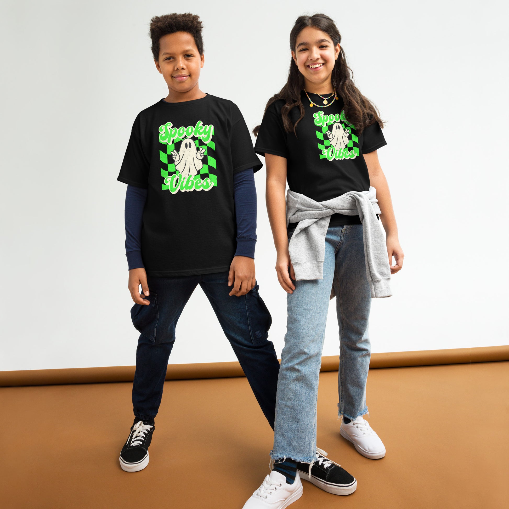 Black Spooky Vibes Child Shirt with a bright green checkerboard pattern and a cute ghost showing the peace sign. The text reads Spooky Vibes. This Halloween tee is perfect for girls and boys! By jaecrece