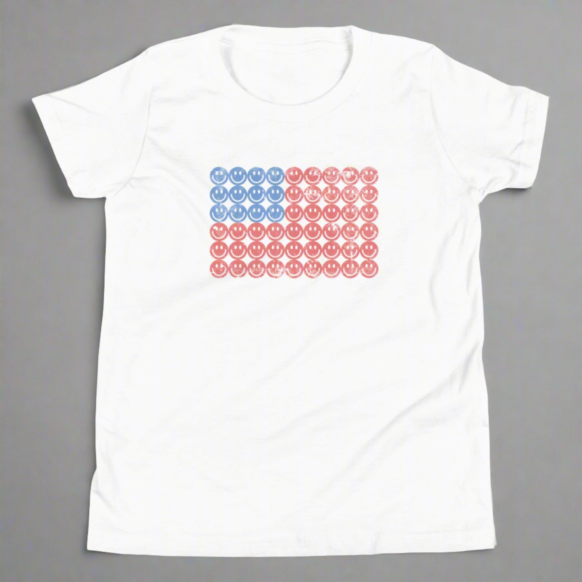 White unisex patriotic shirt for boys and girls. The graphic is an American flag, made up of Blue and Red Vintage smiley faces, by jaecrece.com