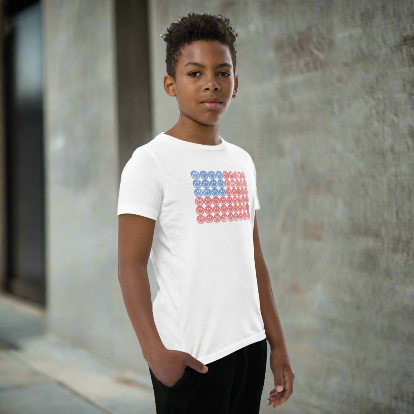 White unisex patriotic shirt for boys and girls. The graphic is an American flag, made up of Blue and Red Vintage smiley faces, by jaecrece.com