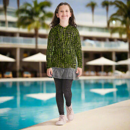 This youth reptile rash guard (sizes 8–20) features a vivid green scale print inspired by dinosaurs and snakes, making it ideal for costumes, beach play, and outdoor fun. UPF sun protection, stretchy comfort, and eye-catching design make it great for water parks or backyard splash days. Perfect for imaginative kids who love reptiles, wild animal themes, and summer adventures in style.
